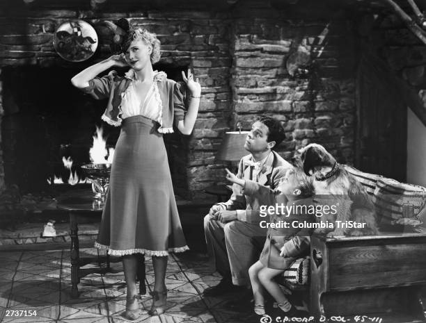 American actor Penny Singleton models a hat as actors Arthur Lake and Larry Simms look on in a still from the film, 'Blondie Takes A Vacation,'...