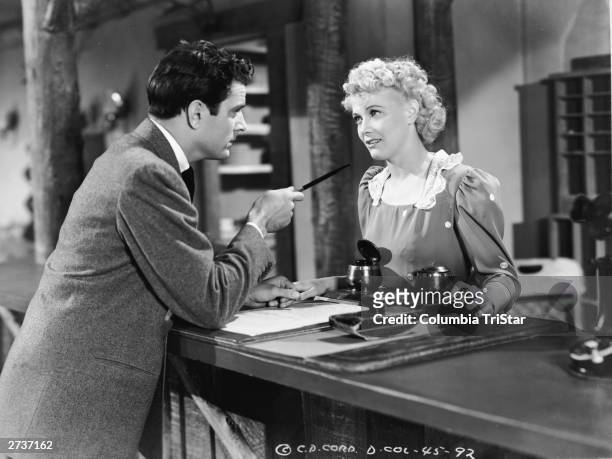 American actor Penny Singleton speaks to an unidentified actor behind a desk in a still from the film, 'Blondie Takes A Vacation,' directed by Frank...