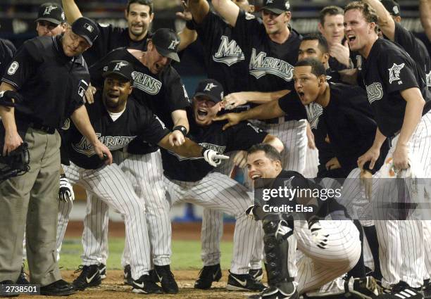 The Florida Marlins await Alex Gonzalez arrival at home plate following his game-winning solo home run against the New York Yankees in game four of...