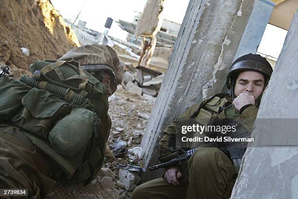 Israeli soldiers take cover between from Palestinian gunfire during an early morning operation to discover a Palestinian smuggling tunnel under a...