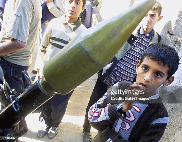 Palestinian boy looks at a masked Hamas group militant during an Israeli incursion November 18, 2003 in the Rafah Refugee Camp, Gaza Strip. Eight...