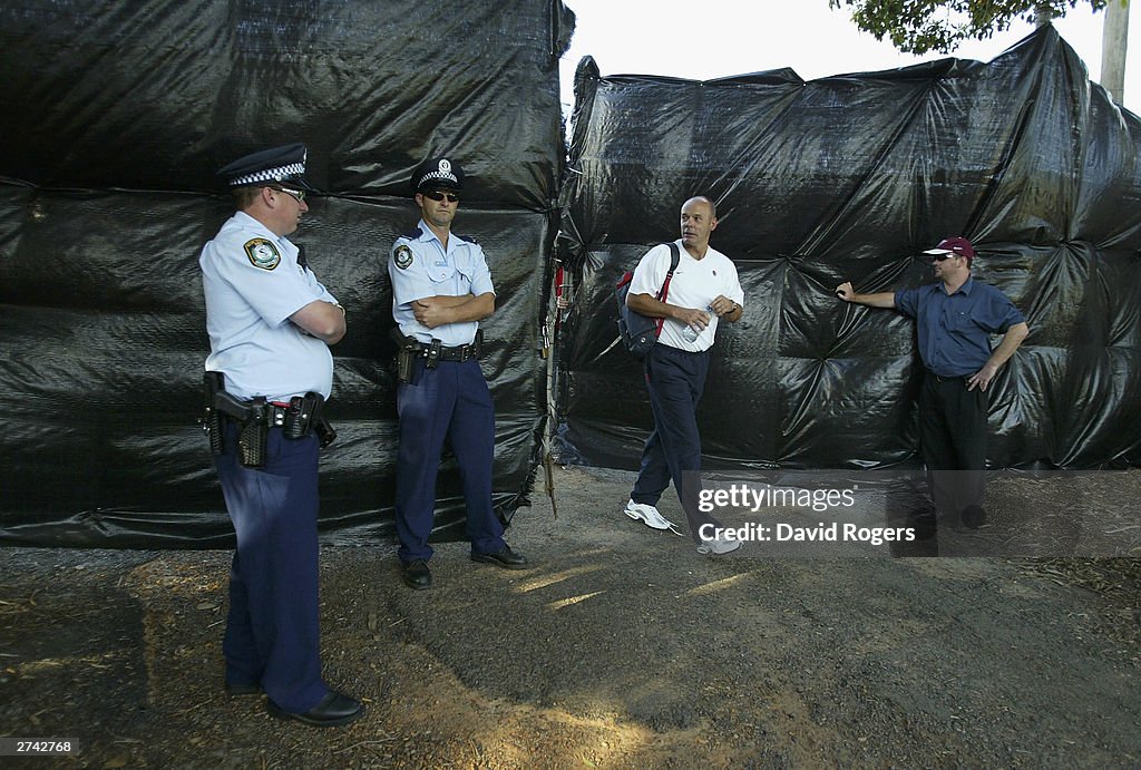 Clive Woodward, the England Head Coach looks at policemen providing security prior to an England training session