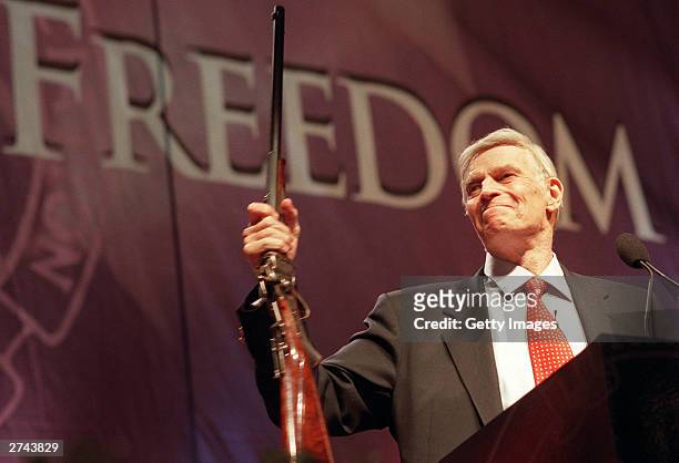 National Rifle Association President Charlton Heston holds up a rifle during his address at the 131st NRA convention at the Reno-Sparks Convention...
