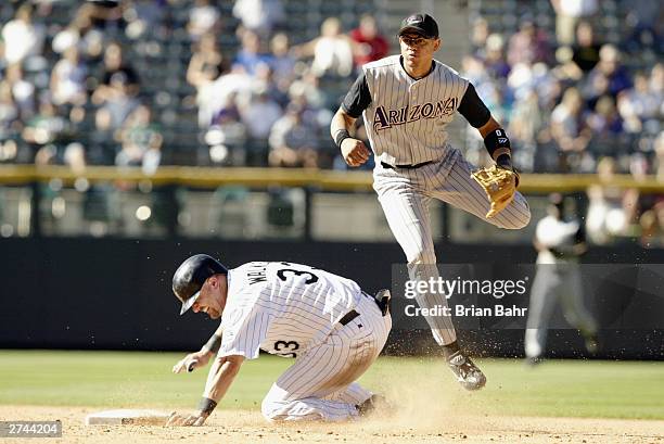 Larry Walker of the Colorado Rockies breaks up a double play at second base as shortstop Alex Cintron of the Arizona Diamondbacks throws to first...