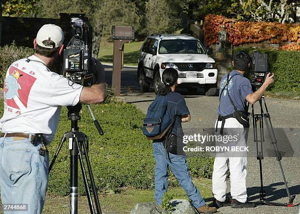 Journalists photograph a car leaving the main entrance to pop star Michael Jackson's estate, known as Neverland Ranch, 19 November 2003, in Los...