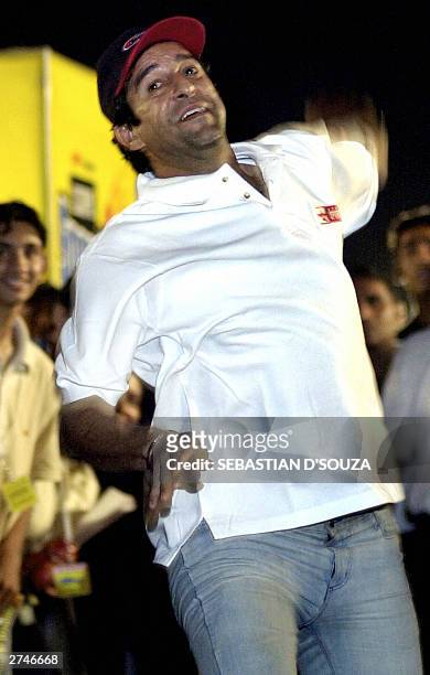 Former Pakistani cricketer and sports comentator for the ESPN-Star Sports channel Wasim Akram demonstrates his bowling technique to aspiring Indian...