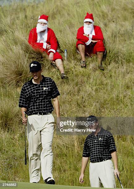 International Team members Adam Scott of Australia and Ernie Els of South Africa line up a putt in front of a pair of Santa Claus' on their way to...