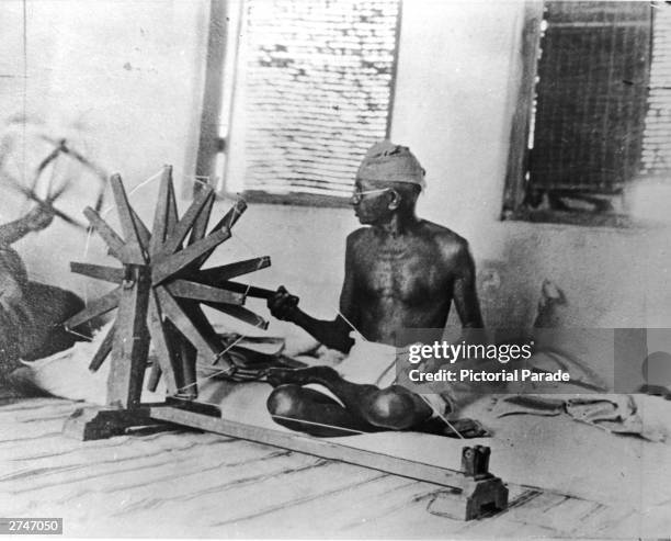 Indian activist Mahatma Gandhi works on a weaving machine, circa 1930.