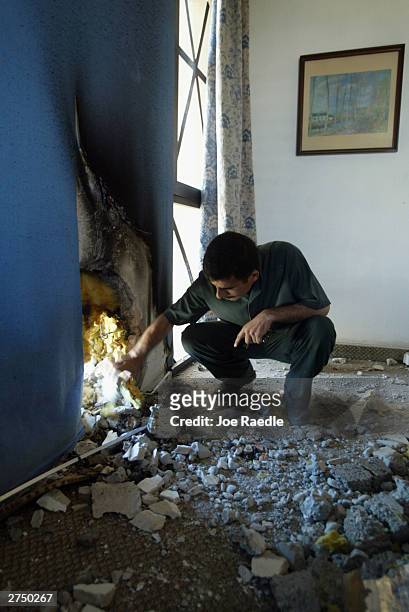 Palestine hotel worker looks at the damage in a hotel room caused by a rocket fired from a donkey cart November 21, 2003 in Baghdad, Iraq. Other...