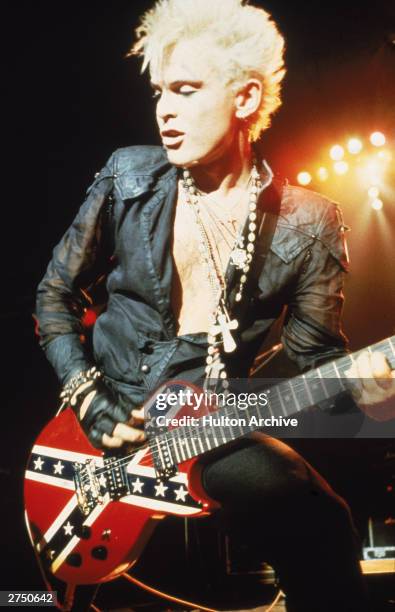 Rock musician Billy Idol plays an electric guitar painted with the British Union Jack flag during a concert, circa 1983.