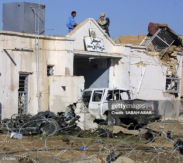 An Iraqi police officer and a US soldier stand on the roof of the Khan Bani Saad police station assessing the damage caused by a suicide bombing...