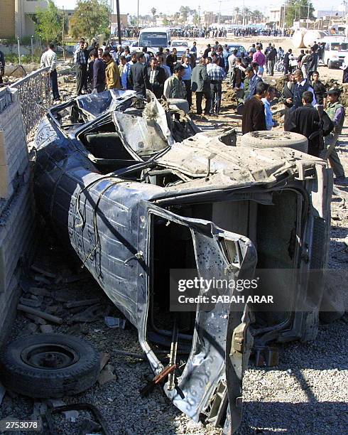 Iraqi civilians gather near a vehicle damaged in a suicide bomb attack outside the police station of Baquba, 60km north of Baghdad, 22 November 2003....