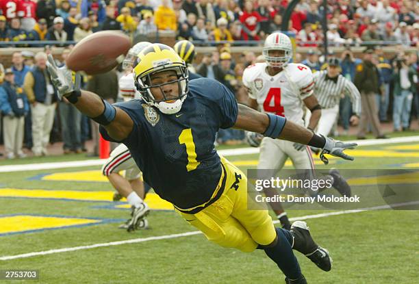 Braylon Edwards of the Michigan Wolverines dives for a pass from John Navarre as Will Allen of the Ohio State Buckeyes watches behind him during the...