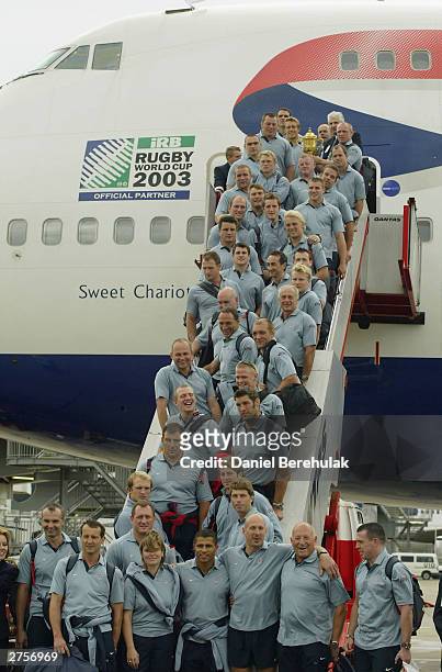 The England team hold aloft the Webb Ellis Trophy on the stairs of the British Airways BA16 aircraft during the departure of the England Rugby team...