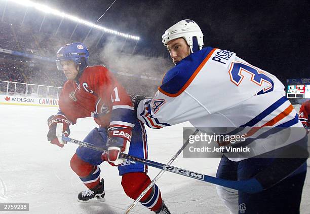 Saku Koivu of the Montreal Canadiens battles against the boards with Fernando Pisani of the Edmonton Oilers during the Molson Canadien Heritage...