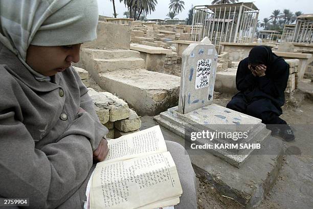 An Iraqi girl reads the Koran while her mother recites the Fatiha, the opening Surat of Koran, over a tomb written on its headstone "late aggrieved...