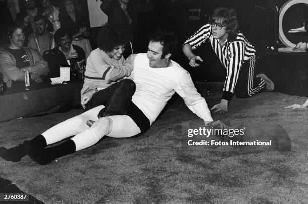 American comedian Andy Kaufman struggles during a match against female wrestler Lena Home, as a referee looks on, Hollywood, California, December...