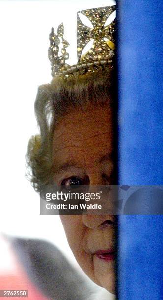 Queen Elizabeth II peers around the side of her carriage as she leaves Parliament on November 26, 2003 in London. The Queen's speech, which...