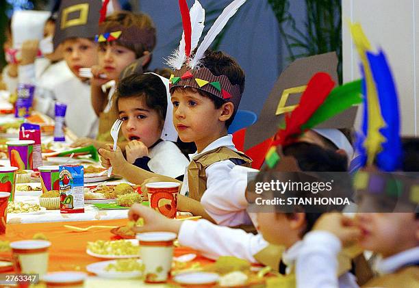 Kindergarden students wearing costumes depicting Native Americans and Pilgrims eat during a Thanksgiving eve lunch, 26 November at the Lycee Francais...
