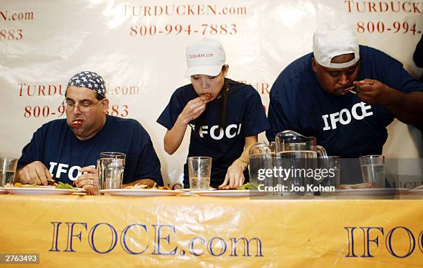 Sonya Thomas, 36-years-old and 100 pounds, Cookie Jarvis and Badlands stuff their mouths during a Thanksgiving eating competition November 26, 2003...