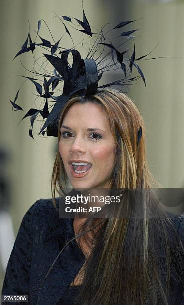 Victoria Beckham poses after her husband English Football captain David Beckham received an OBE 27 November from Britain's Queen Elizabeth II at...