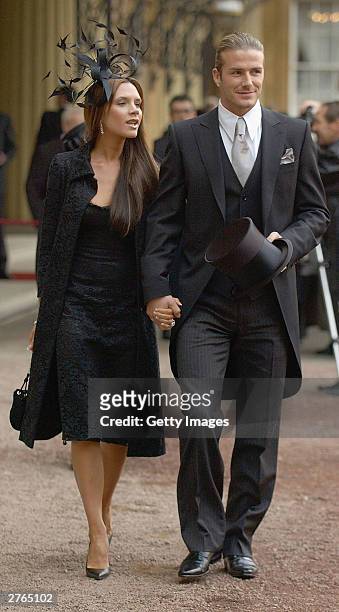England football captain David Beckham walks with his wife Victoria, as he shows off the OBE he received from Britain's Queen Elizabeth II at...