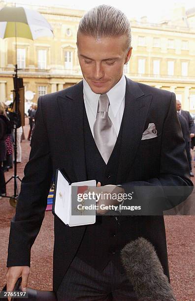 England football captain David Beckham shows off the OBE he received from Britain's Queen Elizabeth II at Buckingham Palace on November 27, 2003 in...