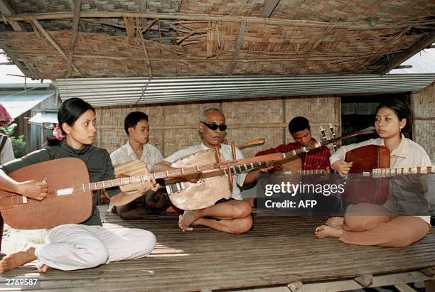 Kong Nei , a 58-year old blind player of the chapei dang veng, a two-stringed instrument similar to a western guitar, teaches his students outside...