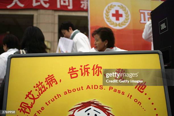 Red Cross official stands behind an Aids awareness placard during an International Red Cross event at a Beijing train station as China marks World...