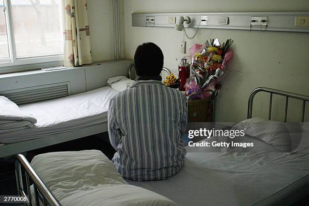 An anonymous patient from Henan province who was infected with HIV when she sold blood to make money, sits on her bed in You'an hospital November 30,...