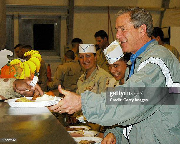 Seen in this handout photo provided by the U.S. Army, President George W. Bush delivers food during a surprise visit on Thanksgiving Day, November...