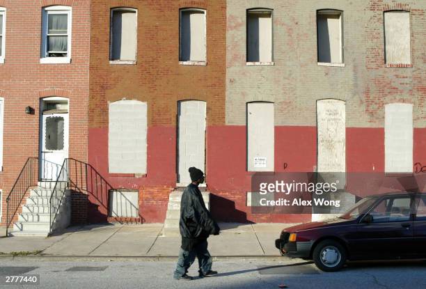 Pedestrian passes boarded up row houses in the Middle East neighborhood, three blocks north of Johns Hopkins University Medical School, December 2,...