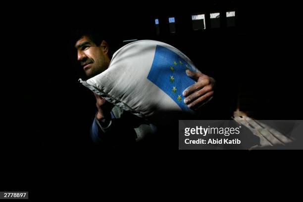 Palestinian refugee carries a bag of flour from the European Union aid distributed by the World Food Program , December 3, 2003 at the northern Gaza...
