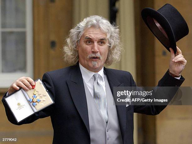 Scottish comedian and actor Billy Connolly shows off his CBE he received 03 December, 2003 from the Prince of Wales at Buckingham Palace, London. AFP...