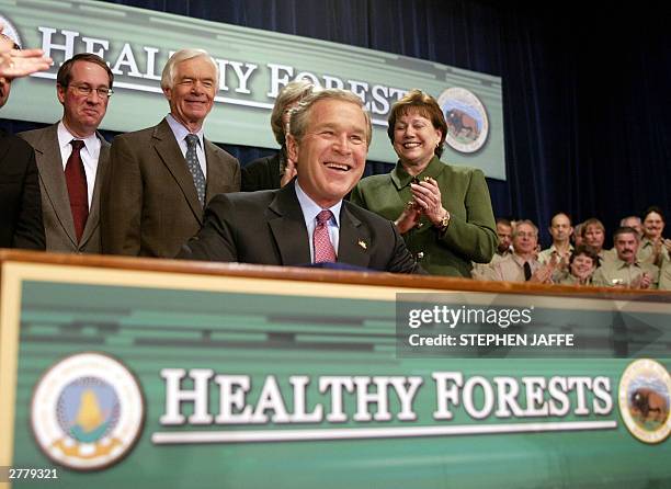 President George W. Bush smiles after he signed the Healthy Forests Restoration Act of 2003 as US Representative Bob Goodlatte , R-VA; US Senator...