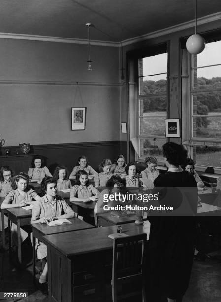 Group of girls from the Dungannon High School sit in a classroom and listen to their teacher read, County Tyrone, Ireland, circa 1950.