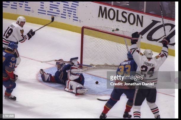 Goaltender Grant Fuhr of the St. Louis Blues fails to stop the puck and the Chicago Blackhawks team rejoices during a NHL game at the United Center...