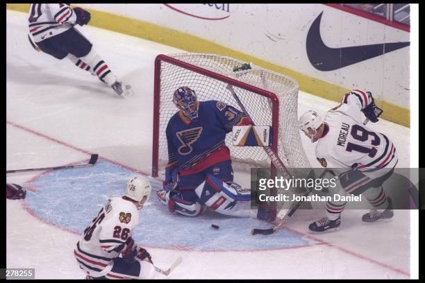Leftwinger Ethan Moreau of the Chicago Blackhawks sends the puck around the corner to goaltender Grant Fuhr of the St. Louis Blues during a game at...