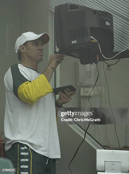 Matthew Hayden of Australia adjust the television set in the players room as he waits for rain to clear and play to start on day two of the first...