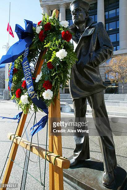 Wreath to memorialize the victims of the attack on Pearl Harbor and pay tribute to the veterans of World War II is placed in front of the Lone Sailor...