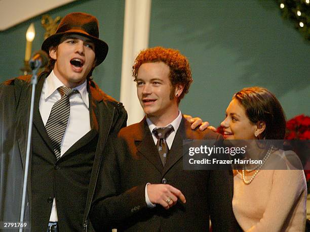 Actors Ashton Kutcher, Danny Masterson and Mila Kunis perform on stage at the Church of Scientology's 11th Annual Christmas Stories Fundraiser to...