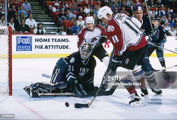 Goaltender Guy Hebert of the Anaheim Mighty Ducks and Colorado Avalanche rightwinger Keith Jones fight for the puck during a game at McNichols Sports...