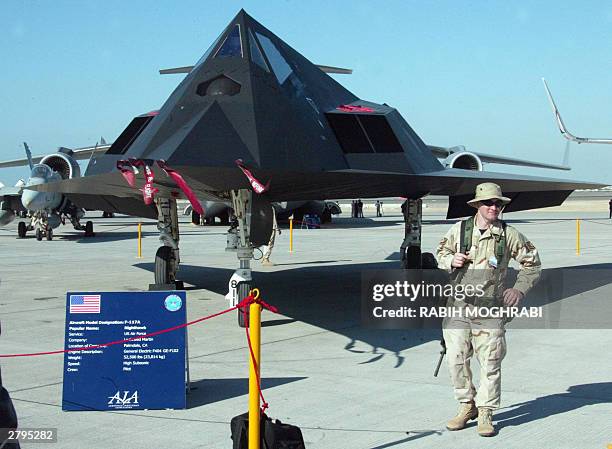 Soldier guards a Nighthawk F-117A at the Dubai Air show 09 December 2003. The United States, Britain and France are jointly setting up with the...