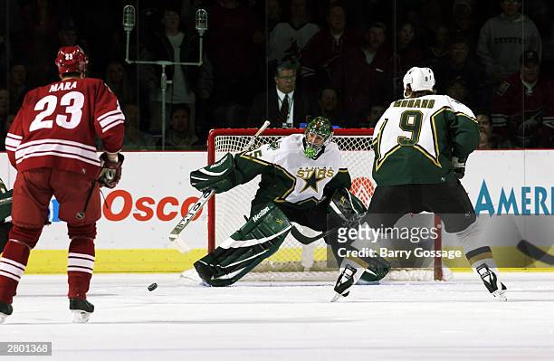 Marty Turco of the Dallas Stars sweeps the puck away from the net against the Phoenix Coyotes December 10, 2003 at America West Arena in Phoenix,...