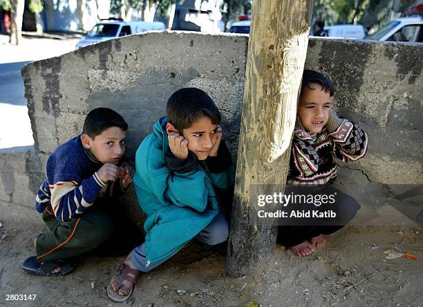 Palestinian children hide behind a wall during clashes between Israeli troops and Palestinian gunmen December 11, 2003 in the Rafah Refugee Camp,...