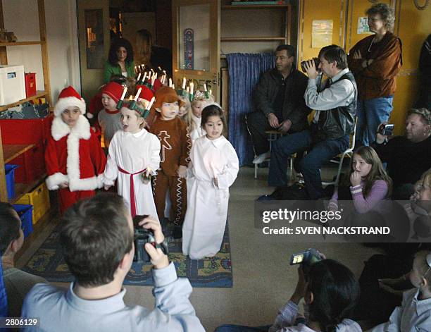 Swedish children dressed as Santa Lucia, Santa Claus and the traditional brown Swedish ginger cookies greet parents as they celebrate the Lucia Day...