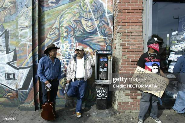 Demonstrator holds a sign as bystanders chat during a rally against California Governor Arnold Schwarzenegger in East Los Angeles 12 December, 2003....