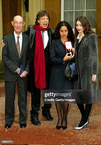 Father Joe with veteran rocker Sir Mick Jagger of the Rolling Stones and daughters Karis and Elizabeth at Buckingham Palace on December 12, 2003 in...