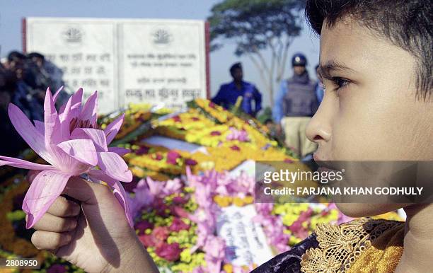 Bangladeshi girl holds a flower at the mausoleum of martyred intellectuals in Dhaka, 14 December 2003 while policemen keep vigil. Bangladesh observed...