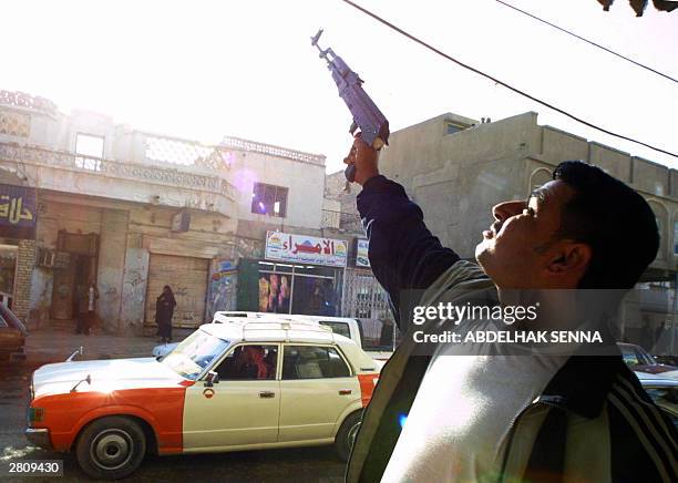 An Iraqi shoots celebratory gunfire in the southern city of Nasiriyah after the capture of ousted Iraqi leader Saddam Hussein in his hometown of...